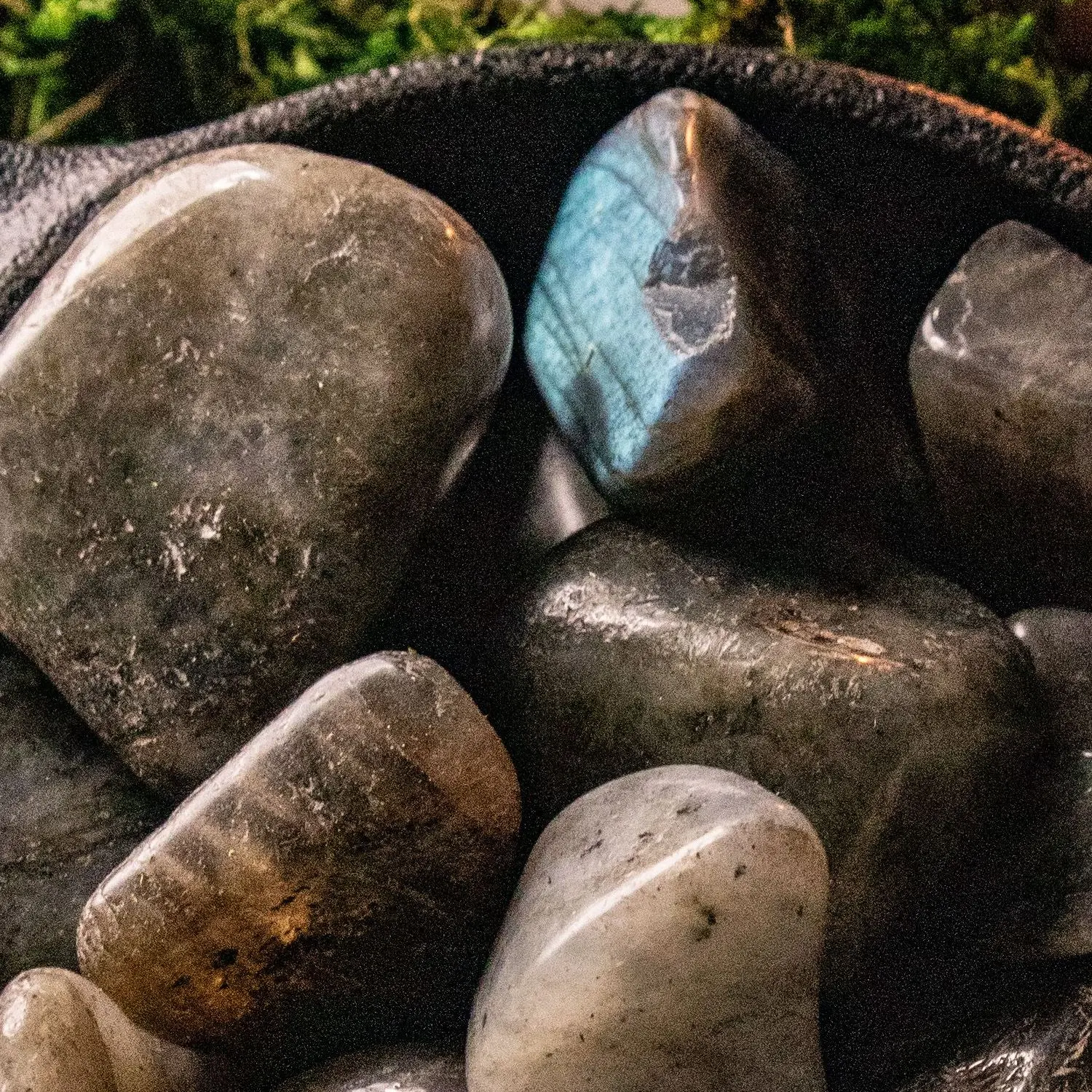 Tumbled labradorite filling a cast iron dish, one stone catching the light and flashing blue
